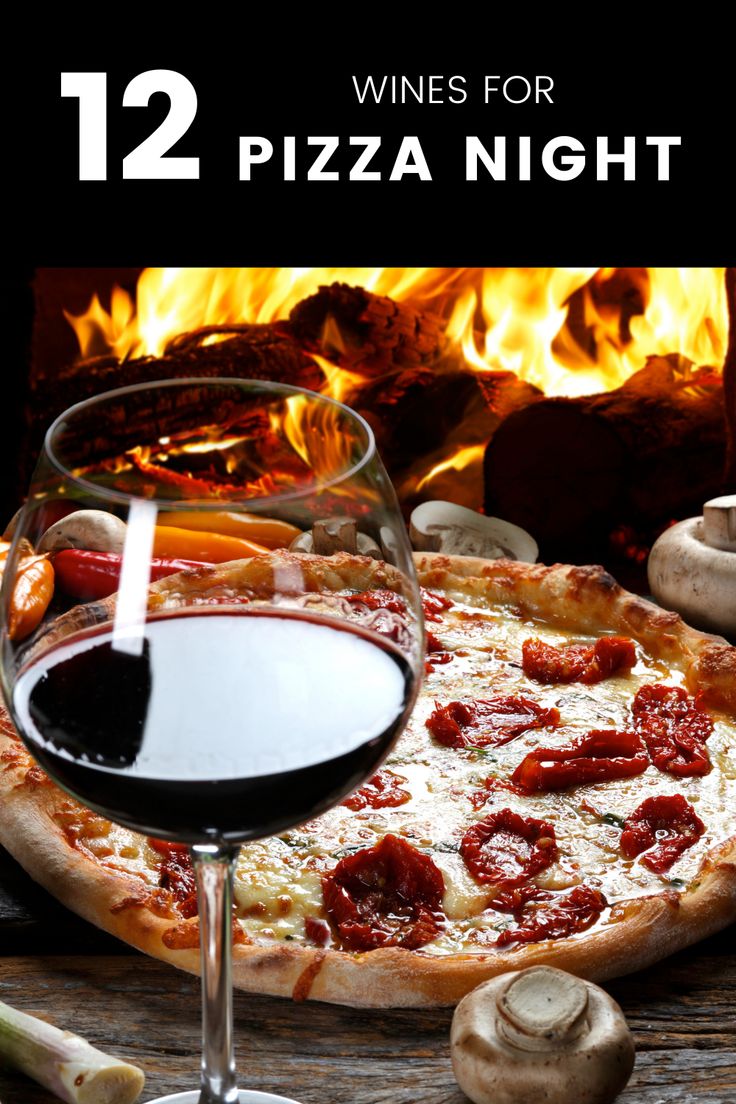 a pizza sitting on top of a wooden table next to a glass of red wine