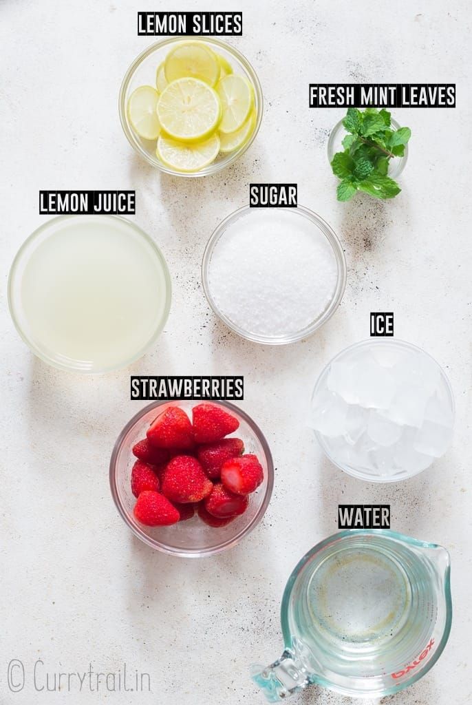 ingredients to make strawberry lemonade on a white counter top, including strawberries and lemons