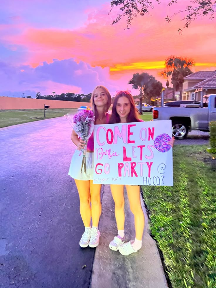 two girls standing on the sidewalk holding flowers and a sign that says, one day it's go party