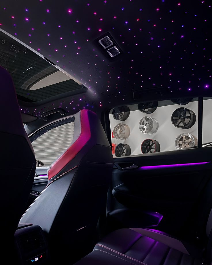 the interior of a car with purple and white stars on the ceiling, along with black leather seats