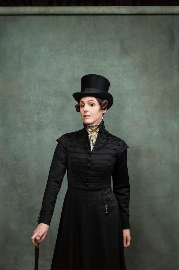 a woman in black dress and top hat holding a cane