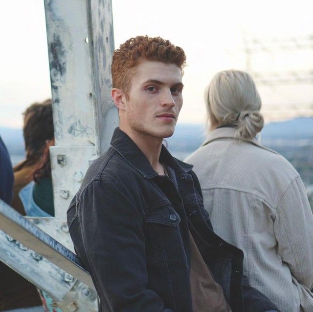 a young man sitting on top of a set of stairs next to a woman standing behind him