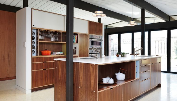 an open kitchen with wooden cabinets and white counter tops, along with black framed windows