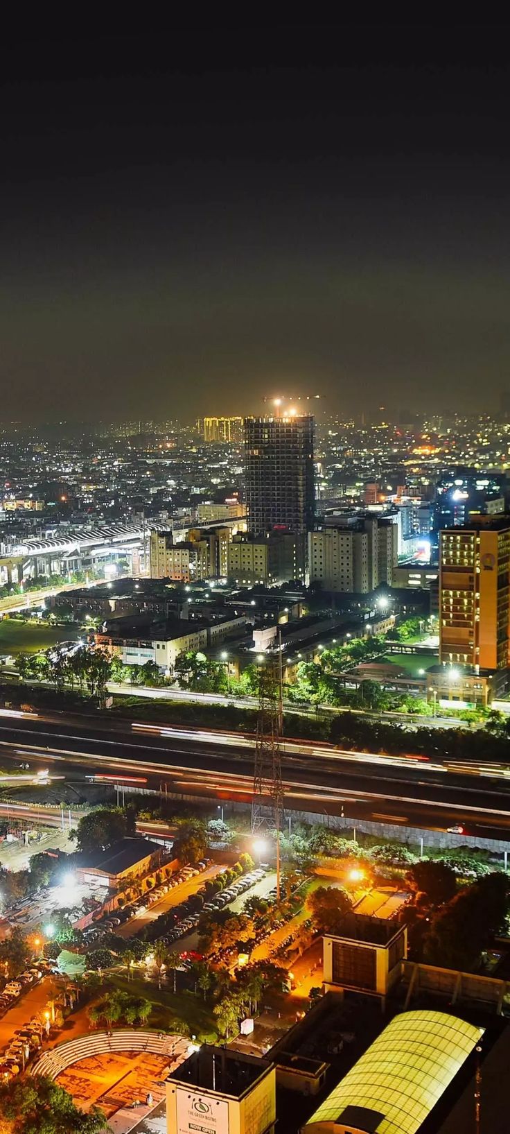 an aerial view of a city at night with lights and buildings in the foreground