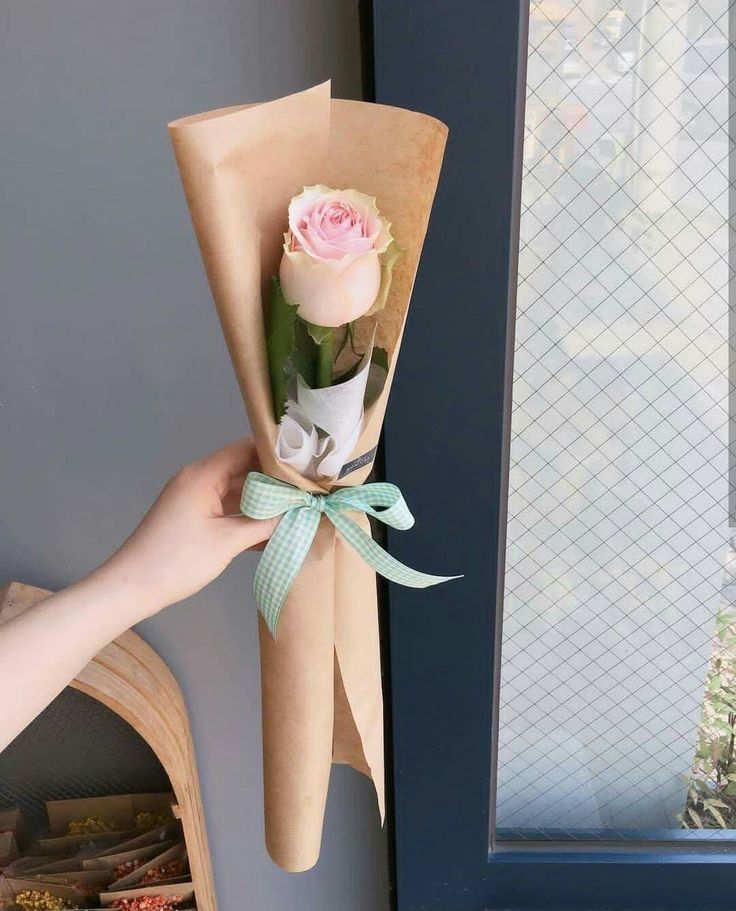 a person holding a bouquet of flowers in their hand with the door open behind them