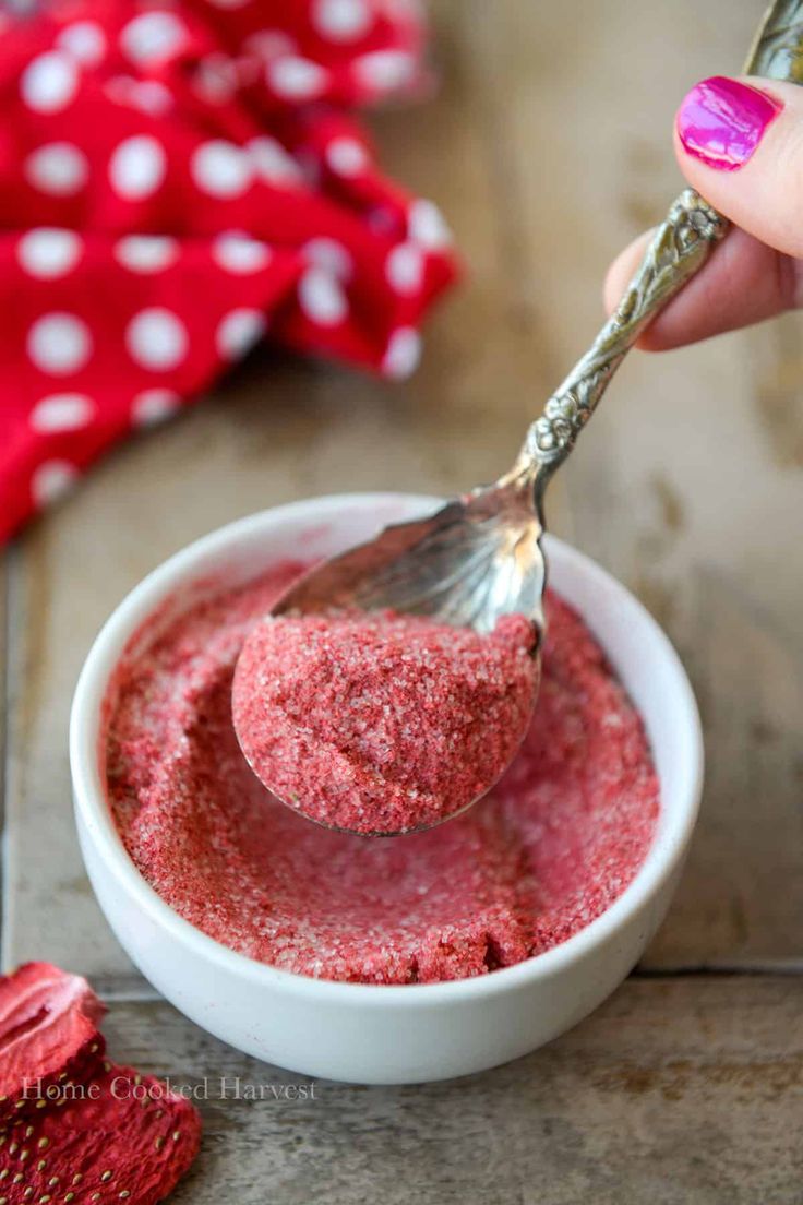 a person holding a spoon over a bowl filled with red food