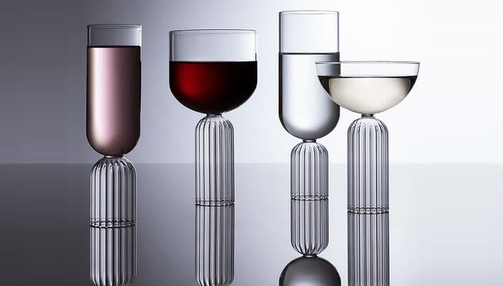 three wine goblets are lined up in front of each other on a reflective surface