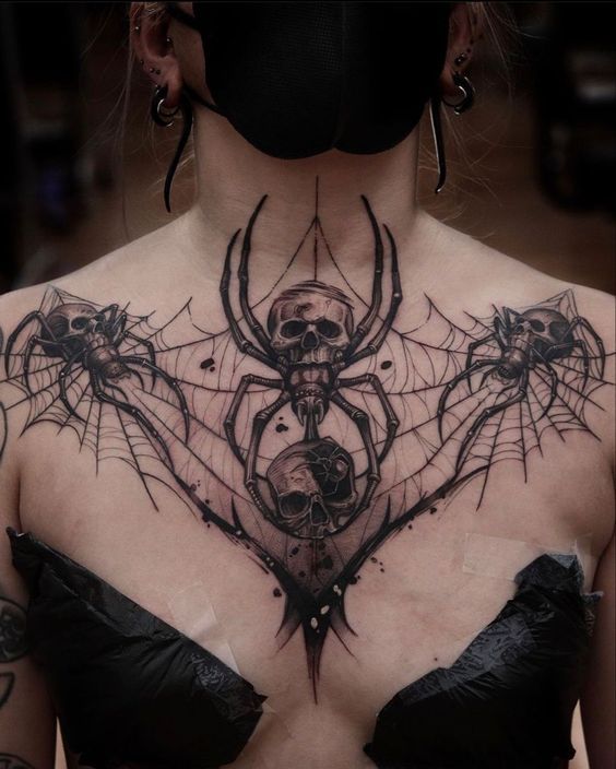 a woman with tattoos on her chest wearing a black mask and spider - web bra