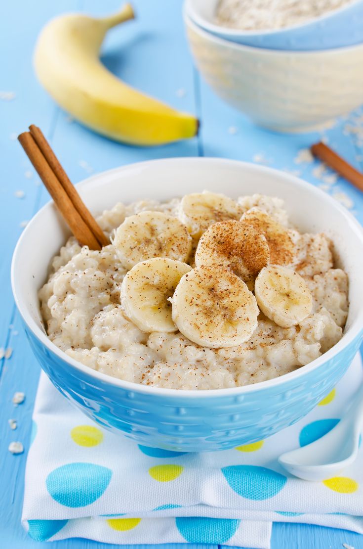 a bowl of oatmeal with bananas and cinnamon in it on a blue table