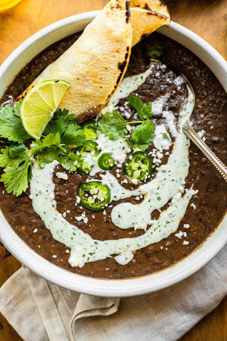 a white bowl filled with black beans and guacamole topped with sour cream