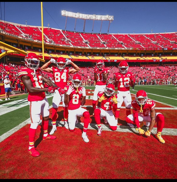 a group of football players standing on top of a field in front of an empty stadium