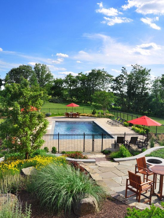 an outdoor patio with tables and chairs next to a swimming pool surrounded by greenery