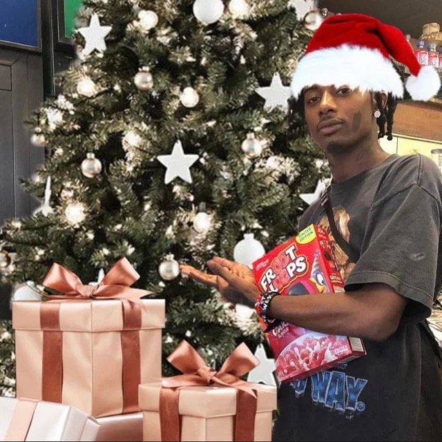 a man in a santa hat standing next to a christmas tree with presents on it