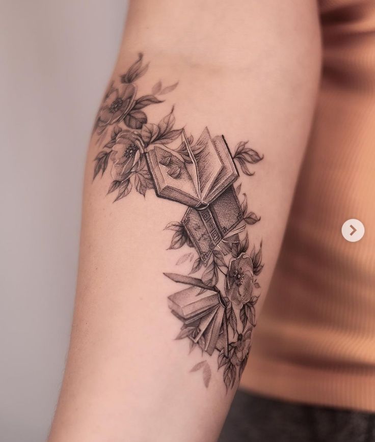 a woman's arm with a cross and flowers tattoo on the left side of her arm