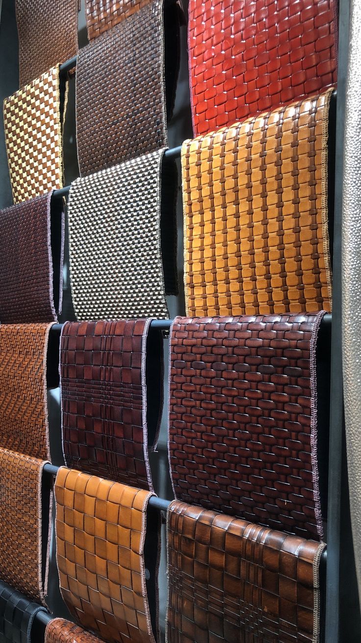 many different colors and patterns of woven material are arranged on the wall in this display