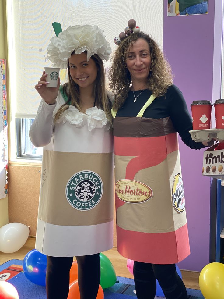 two girls dressed up as starbucks characters holding cups in their hands and standing next to each other