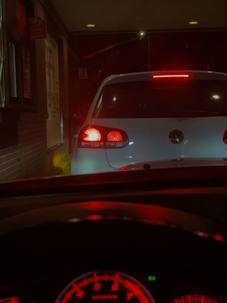 a white car driving down a street at night