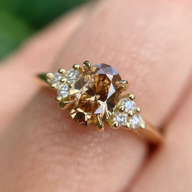 a woman's hand holding an orange and white diamond ring with two diamonds on it