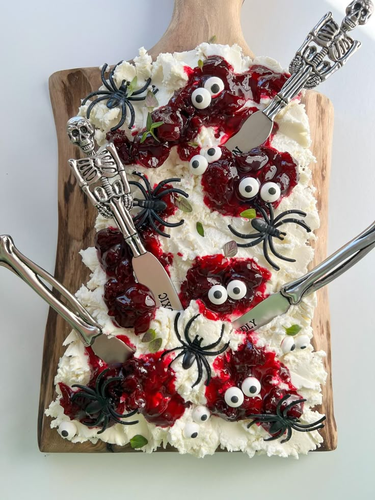 a homemade halloween cake with white frosting and red toppings on a wooden cutting board