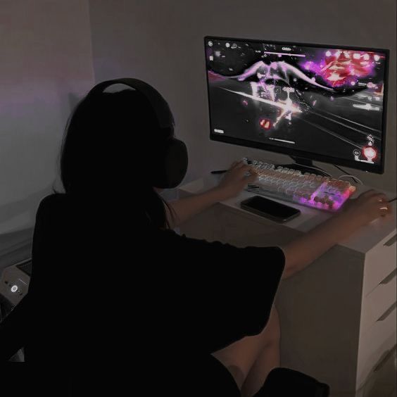 a person sitting in front of a computer with headphones on and playing video games