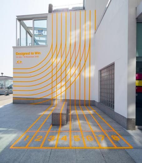 an orange line on the ground in front of a building with a sign that says designing to win