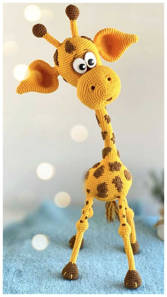 a crocheted giraffe standing on top of a blue blanket