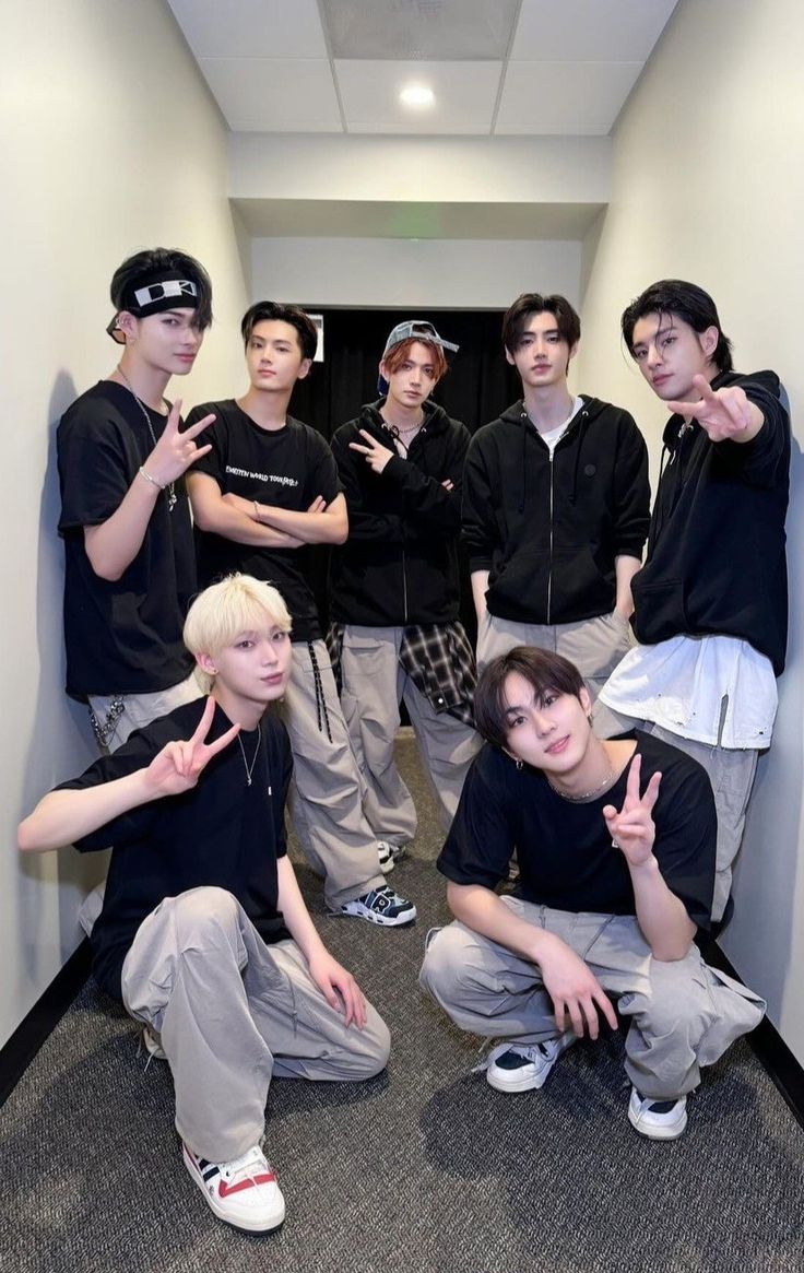 group of young men posing for photo in hallway with one pointing at camera and the other holding up two fingers