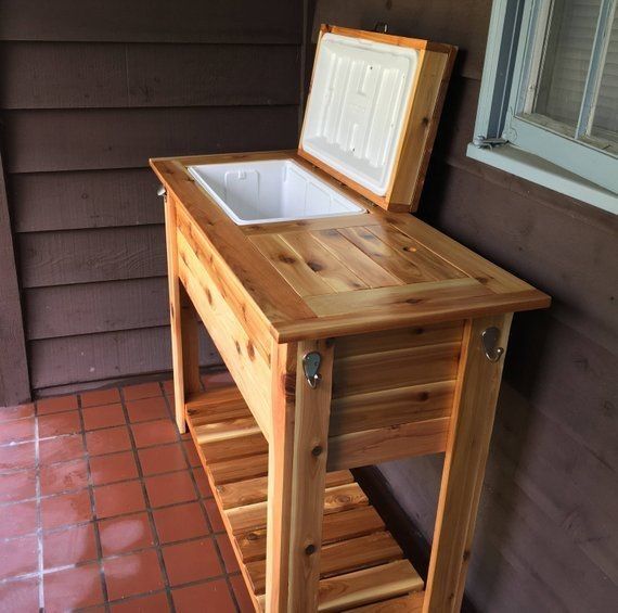 a wooden table with an ice chest on it's side and a window in the background