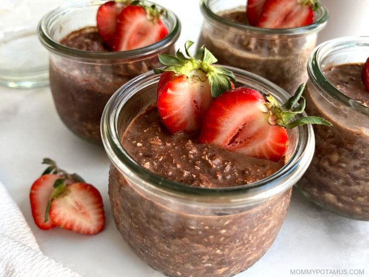 three mason jars filled with chocolate chia pudding and topped with strawberries on top