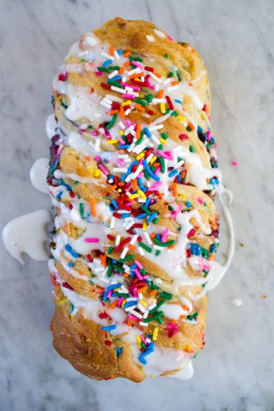 sprinkles and white frosting on top of a loaf of bread