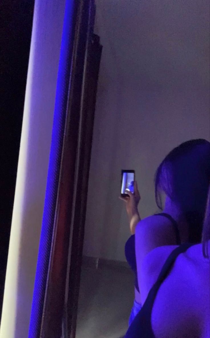 a woman is looking at her cell phone in the mirror while she's taking a selfie