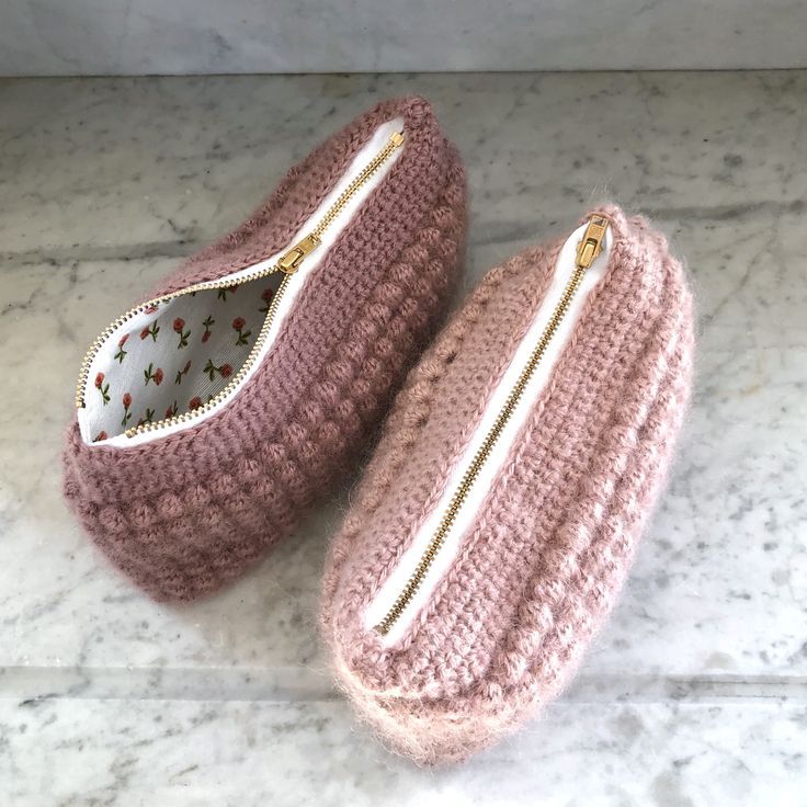 two pink crocheted purses sitting on top of a marble counter