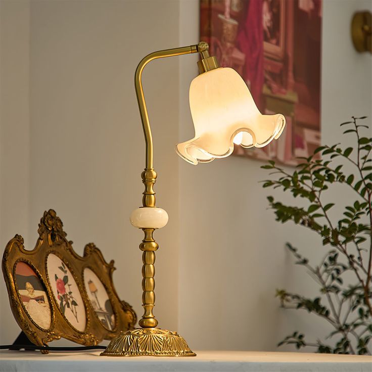 a lamp that is sitting on top of a table next to a clock and potted plant