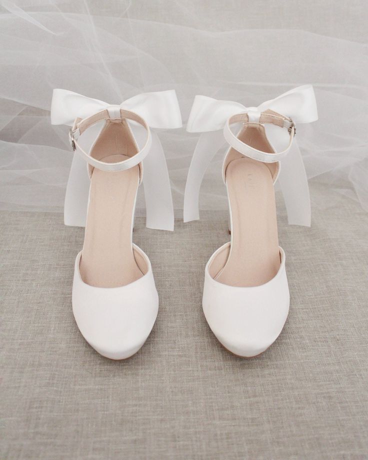 the bride's shoes are all white and have bows at the ankle straps