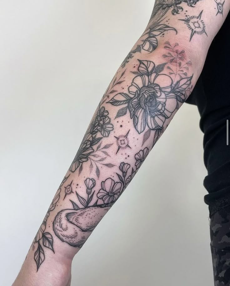 a woman's arm with flowers and birds tattoo on her left arm, while the other arm is in full bloom