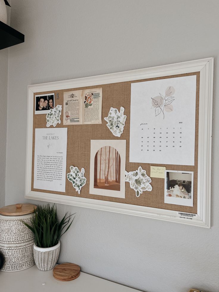 a cork board with pictures and magnets on it next to a potted plant