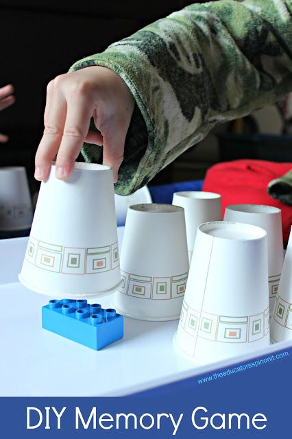 a young boy is playing with legos and cups on a table in front of other children