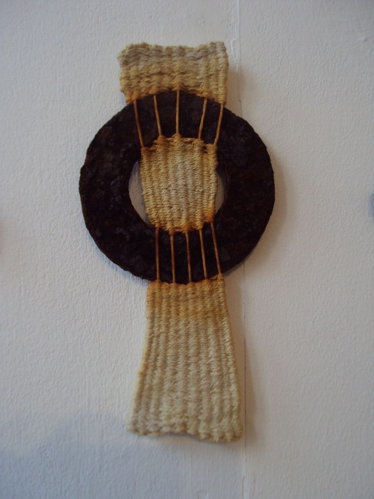 a piece of woven material hanging on the wall next to a black and brown object