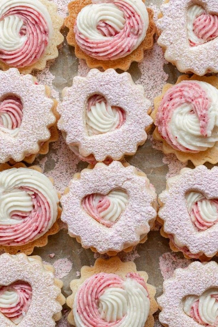 some pink and white cupcakes with frosting in the shape of a heart