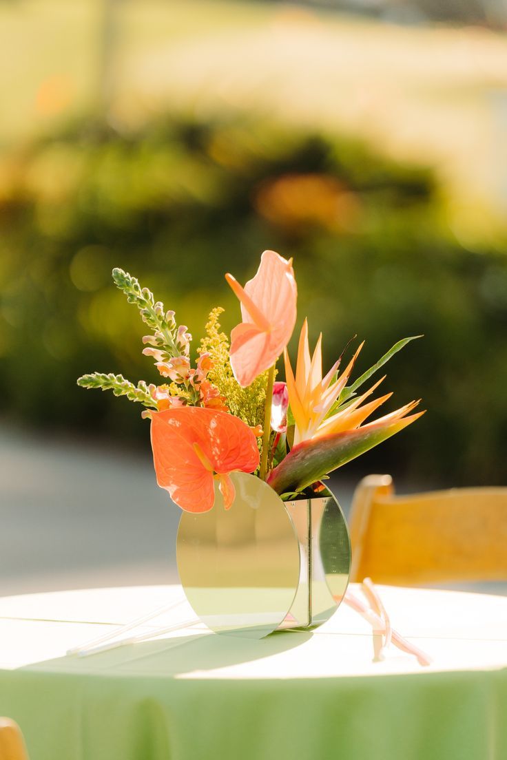 an arrangement of flowers is placed in a vase on a table with green cloths