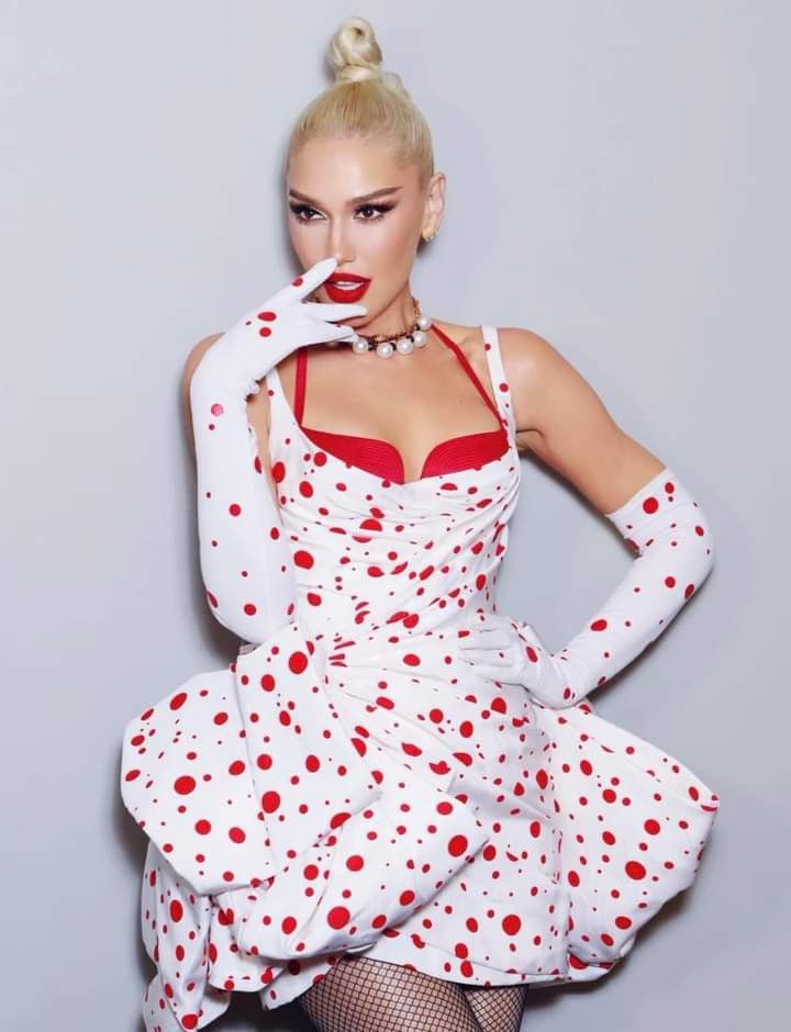 a woman in white and red polka dot dress posing with her hands on her hips