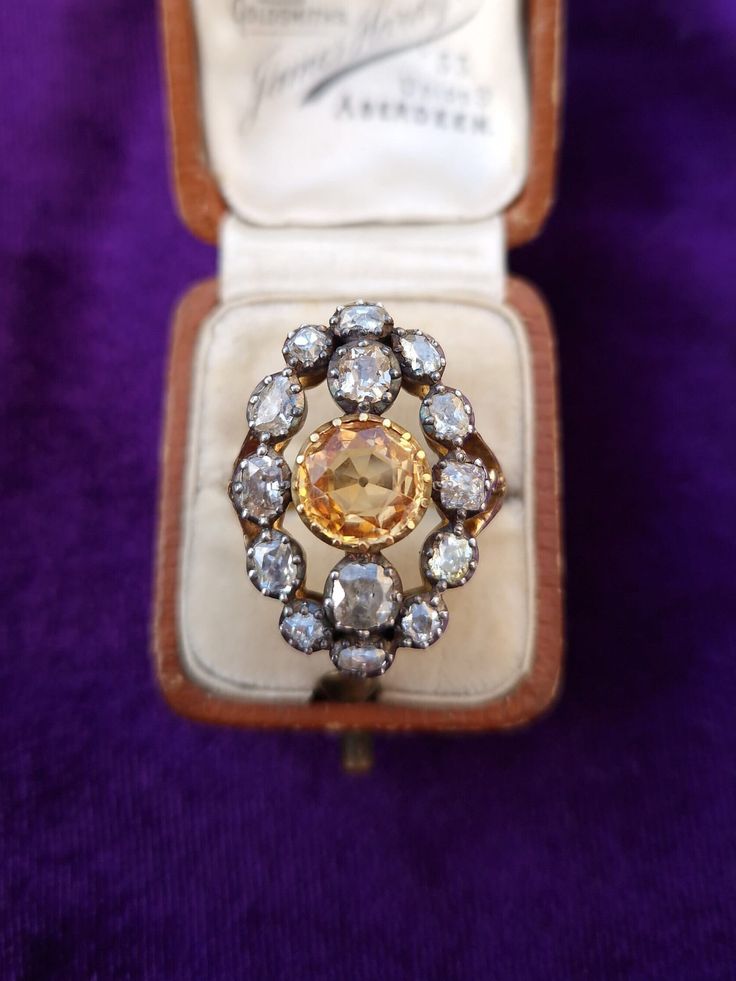 Antique Diamond & Topaz 18ct Gold & Silver Navette shaped Ring If you are a collector of antique jewellery and are looking for a bold statement piece, then this spectacular antique 19th century Georgian ring will not disappoint. The old cut topaz is stunning, it has a deep golden honey colour with excellent clarity. It is set in a crimped open backed setting in 18ct yellow gold. The topaz is surrounded by 14 old mine cut diamonds. The diamonds are each encased in silver crimped setting with a closed 18ct gold back. Each diamond has been hand cut and therefore each one differs from the next, they are not uniform and there are some colour variations which adds to the authenticity and charm. The ring has trifurcated shoulders and the band has a partially engraved shank. * Valuation certificat Antique Gold Sapphire Ring, Heirloom Gold Topaz Ring With Rose Cut Diamonds, Heirloom Topaz Rings With Rose Cut Diamonds, Antique Gold Topaz Ring With Center Stone, Antique Topaz Jewelry, Vintage Gold Sapphire Ring With Single Cut Diamonds, Antique Topaz Ring For Wedding, Vintage Topaz Ring With Center Stone, Victorian Style Topaz Ring