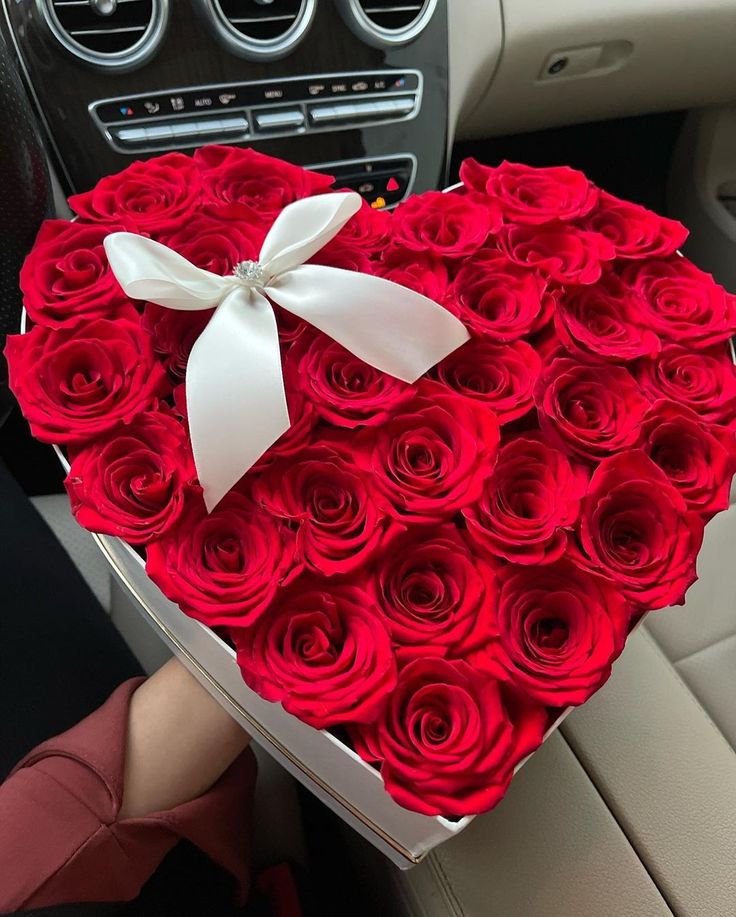 a heart shaped box filled with red roses in the back seat of a car,