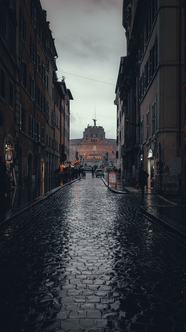 an empty city street with cobblestones on both sides and buildings in the background