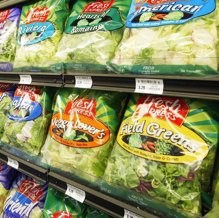 bags of salad are on display in a grocery store