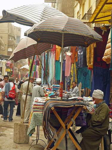 an outdoor market with people shopping and selling umbrellas