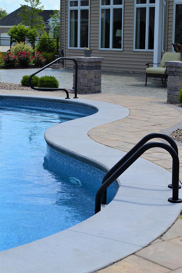 an empty swimming pool with steps leading up to it and a house in the background