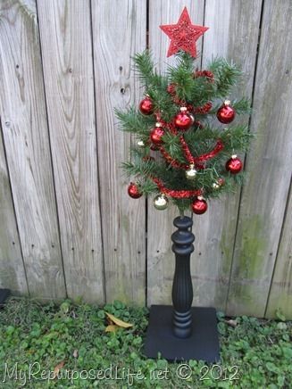 a small christmas tree in a black vase with red and gold ornaments on the top