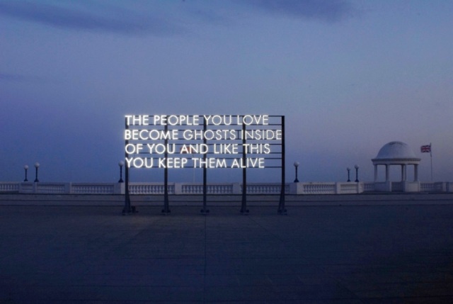 an illuminated sign sitting on the side of a road in front of a white dome