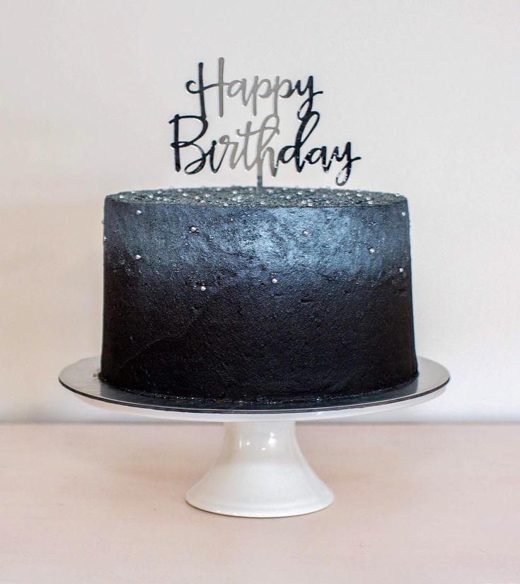 a black birthday cake sitting on top of a white plate